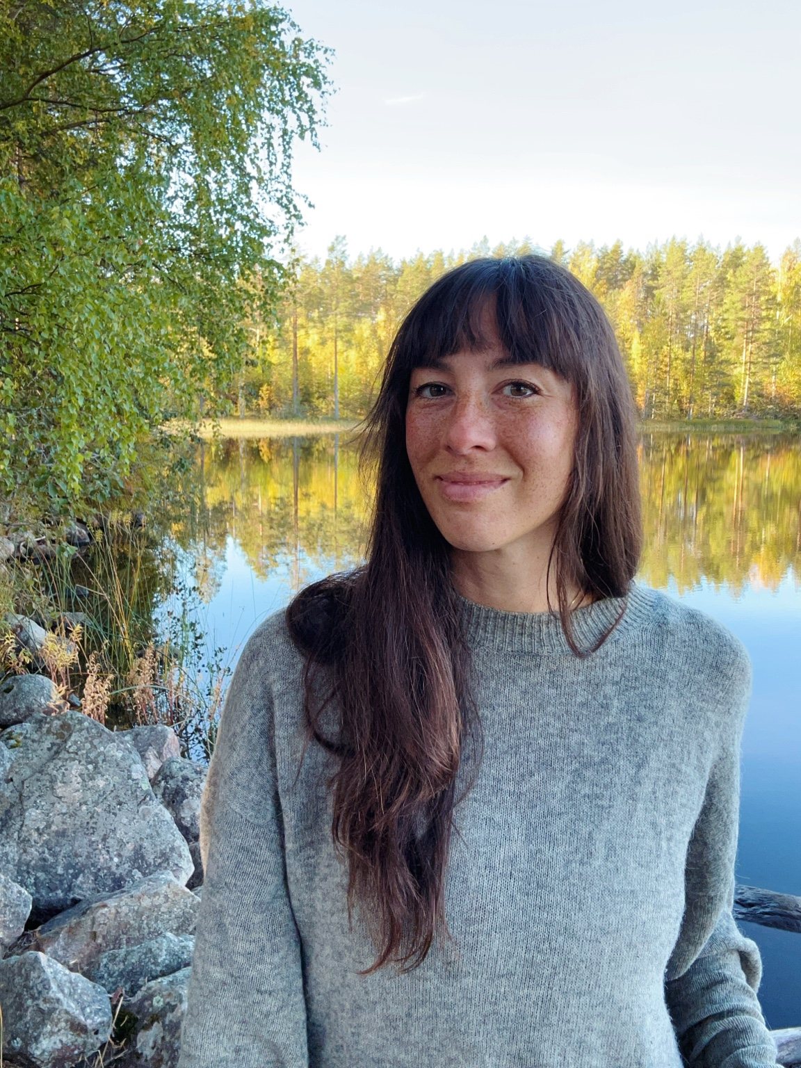 Hannah i grå tröja vid sjön med ett varmt leende